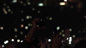 Close up man waving hands with smartphones with flashlight in a live concert crowd people festival music performance celebration rock stage event party disco light nightlife show slow motion