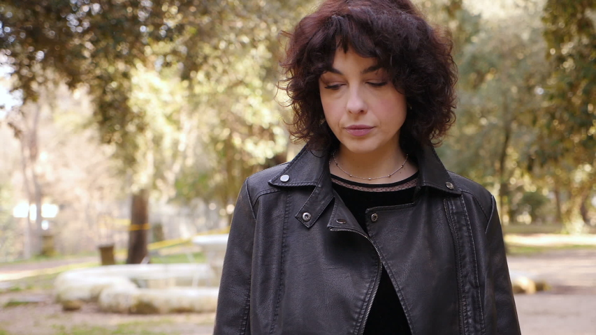 Confident serious attractive woman in the park,straing at camera-slow motion