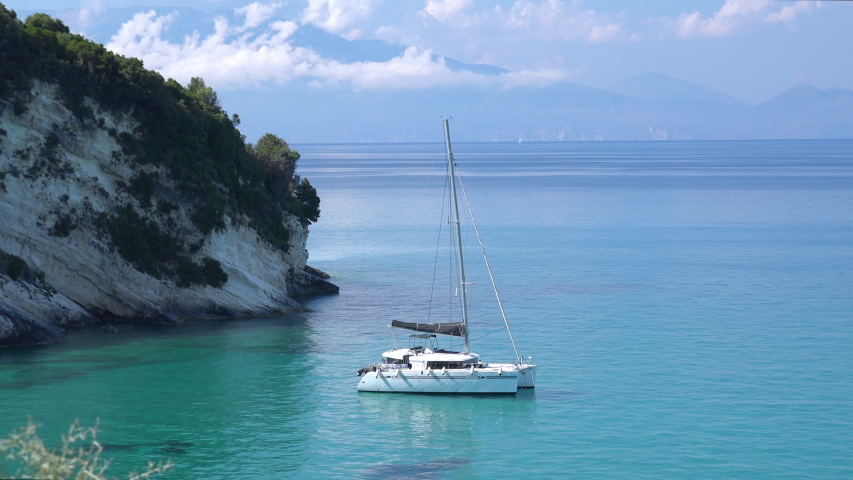 Beautiful panorama of luxury yacht floating turquoise Ionian Sea near rocky coastline. Top view of Zakynthos island. Mediterranean paradise and breathtaking landscape of blue skyline, Greece