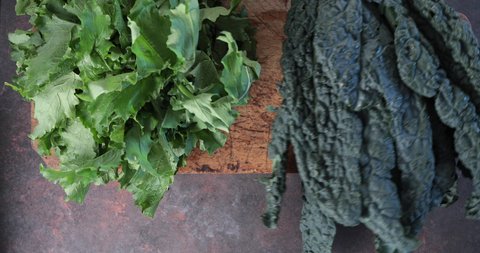 Turnip greens and Tuscan black kale on wooden table - Fresh bio leafy vegetables on a wooden cut board top view