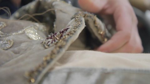 Close up of a woman hands sewing decoration to the dress. dressmaker creates an item of clothing. handwork. putting needle through fabric