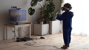 modern life of youth. The latest electronic technology in everyday life. little boy plays at home in a virtual reality helmet