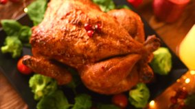 Christmas Roasted Chicken Dinner. Winter Holiday table served, decorated with candles. Delicious Steamed Roast chicken over wooden background with Christmas gifts, table setting. Dolly shot 4K UHD
