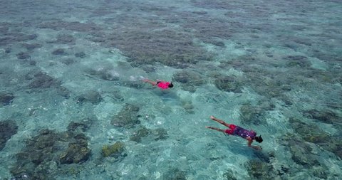 Couple Snorkelling, Exploring The Coral In The Maldives