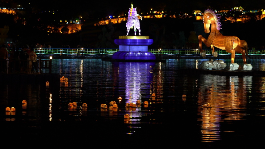 Jinju Namgang Yudeung or lanterns festival with traditional lanterns of different size floating on Nam river and illuminated fortress in background in Jinju South Korea
