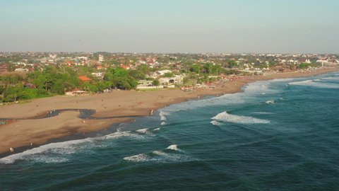 The beaches of Canggu during sunset. With beach clubs, hotels, resorts, restaurants and surfers. Aerial shot.