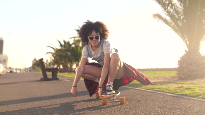 hipster skater woman carrying longboard on sunny day past palm trees Royalty-Free Stock Footage #1039715909