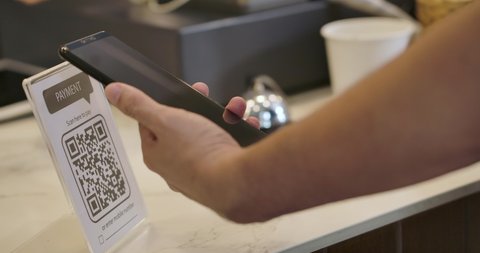 Customer using smartphone for scanning QR code for paying at coffee shop. 4K QR code cashless payment concept.