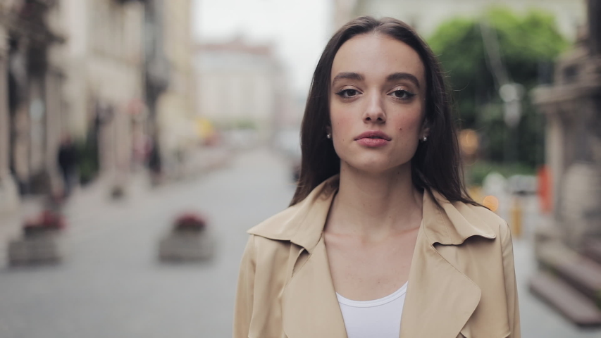 Portrait of Beautiful Young Girl Turning her Head to Camera Standing at City Background Close Up