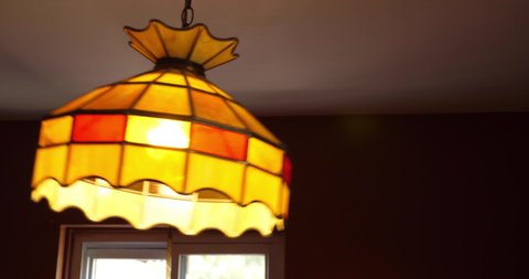 A closeup view of a wobbling dining room lamp as it flickers. Perhaps after an earthquake.  	