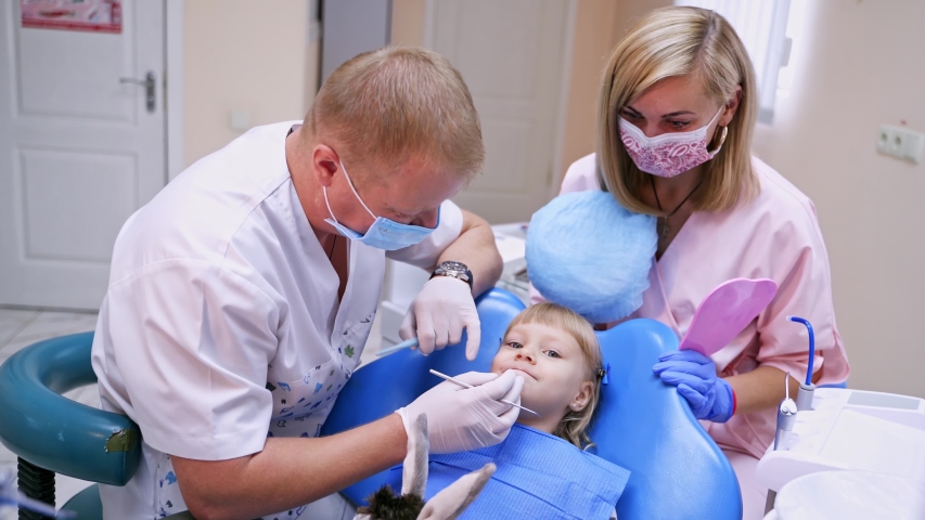 Little child in stomatology chair prepares for teeth check up- close up video. Assistant helps to provide procedures. Healthy teeth concept video.