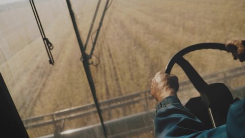Man driving a combine and harvesting the wheat.