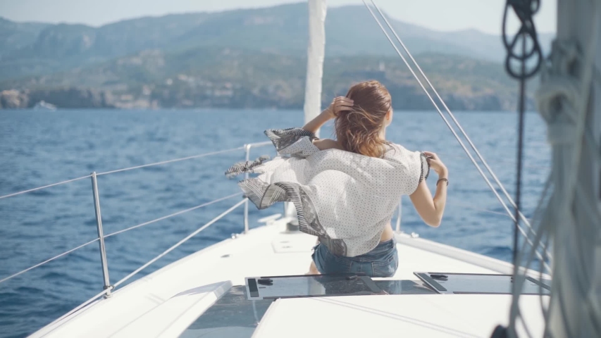 Beautiful woman on a yacht enjoys the journey on the background of the islands of Ibiza or Mallorca. Luxury yacht near the balearic islands Royalty-Free Stock Footage #1039734866