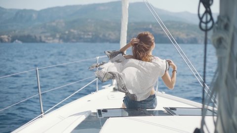 Beautiful woman on a yacht enjoys the journey on the background of the islands of Ibiza or Mallorca. Luxury yacht near the balearic islands