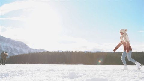 Young couple ice skating in winter outdoors on a frozen lake in Canada, Slow motion 