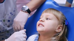 Little child in stomatology chair opens her mouth wide and shows her teeth to the doctor - close up video.