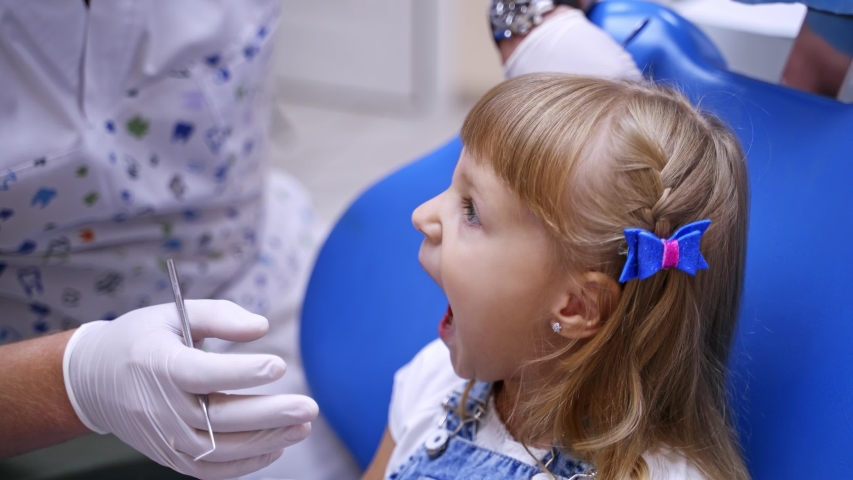 Little child in stomatology chair - close up. Cute blonde girl opened her mouth for teeth check up. Health concept video.
