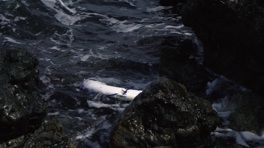 Lifebuoy in the Mediterranean Sea near the rocky coast. Close-up. Dangerous route of migration of refugees from Africa to Europe by sea