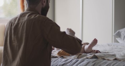 Father changing diapers of baby in bedroom