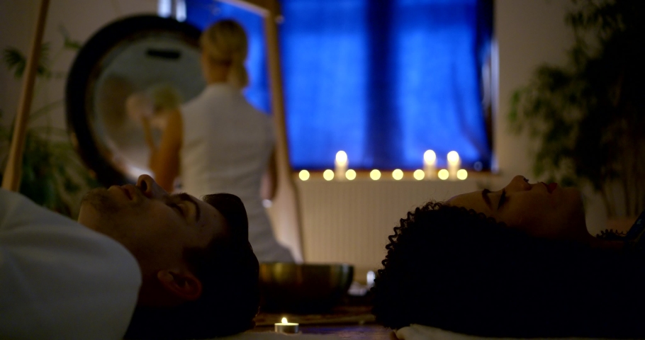 young man and woman are lying on floor with closed eyes and listening playing violinist, family music therapy