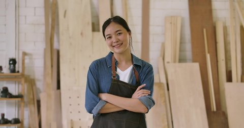 Close-up portrait of young attractive carpenter standing with crossed arms smiling positively into camera. Slow motion