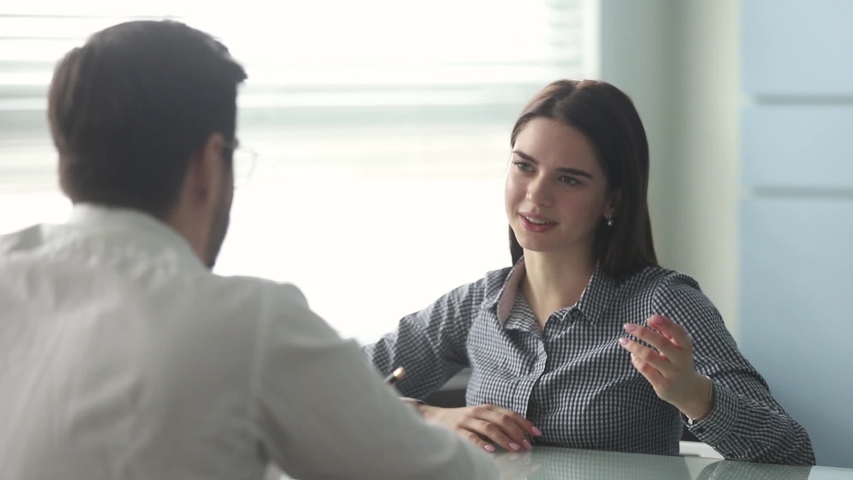 Rear view company HR manager interviewing young woman candidate for vacancy sit at desk in office, candidature answering on questions feels confident. Human resources, recruitment, employment concept Royalty-Free Stock Footage #1039779377