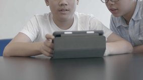 Asian preteens boys using tablet computer at library . Two boy drawing on tablet computer with smile face.