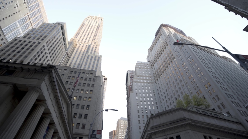 New York City , New York / United States - 10 02 2019: Moving through crowded FINANCIAL DISTRICT of NEW YORK CITY to a low angle shot of the WALL STREET skyscrapers