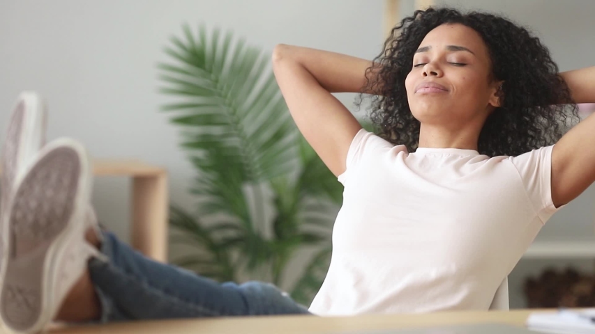 Calm black woman put legs on table leaning on chair enjoy day nap resting in modern office room, african female closed eyes smiling relaxing at home, no stress, filling with positive thoughts concept Royalty-Free Stock Footage #1039782776
