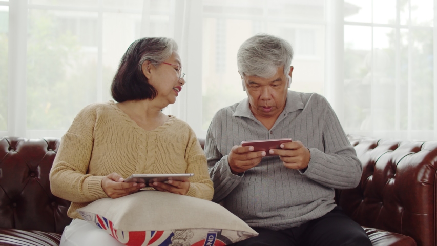 4K locked shot senior wife holding tablet in hand and joyful to banter her husband while playing games on smartphone until his defeated. | Shutterstock HD Video #1039786838