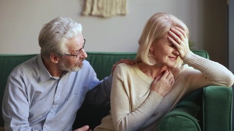 Elderly spouses sitting on couch aged wife crying feels desperate worried anxious husband comforting beloved woman showing empathy, sad life event, senile disease diagnosis, health problems concept