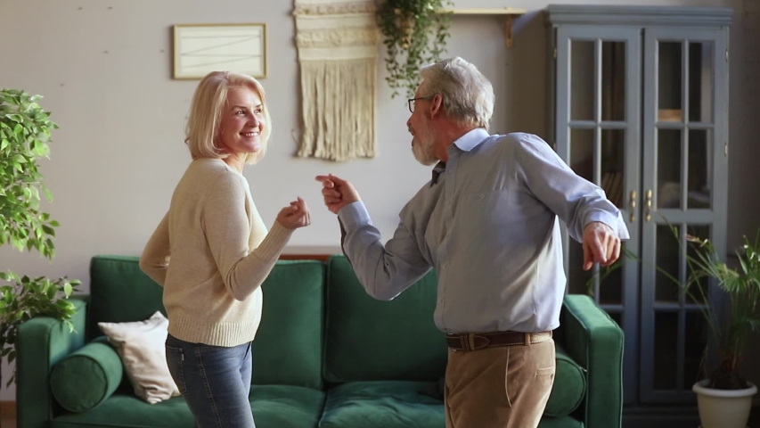 Elderly spouses standing in living room listening energetic music dancing together, senior hoary rock-n-roll dancers enjoy life feels happy and healthy spending active free time on weekend at home Royalty-Free Stock Footage #1039788467