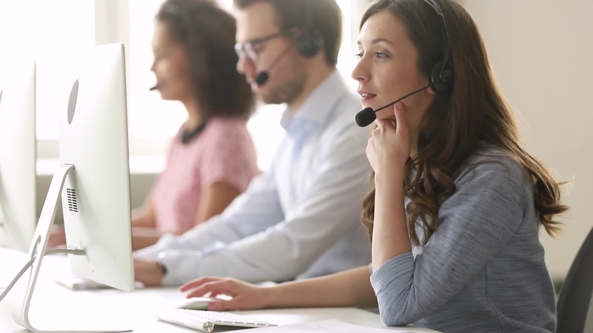 Service phone operators sit at shared desk focus on sales agent woman in headset use pc answers incoming calls talk with client provide professional support to customers sell company product concept | Shutterstock HD Video #1039793780