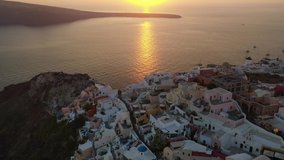Aerial drone video of unique sunset over picturesque village of Oia with beautiful golden colours, Santorini island, Cyclades, Greece