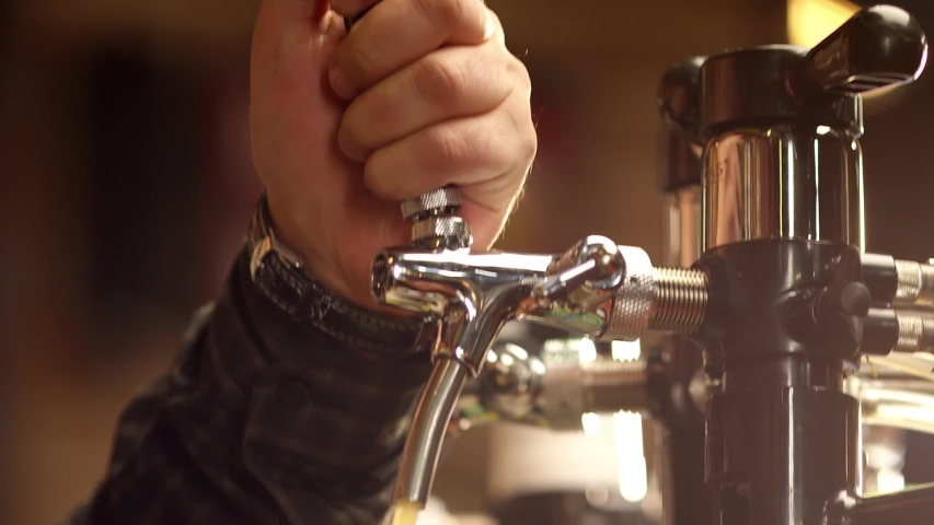 Pouring cold beer into glass. Bartender pouring craft beer in the bar. The hand of a master brewer pour from keg a light draft beer foam . Stout, Light, Unfiltered beer, ready to drink . Slow motion . | Shutterstock HD Video #1039802729