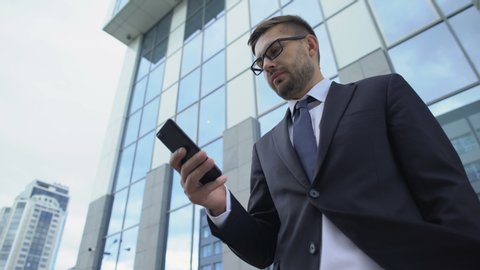 Businessman checking messenger using cellphone outdoors, communication apps