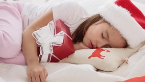 Lovely video of little girl in santa hat, sleeping with Christmas present.