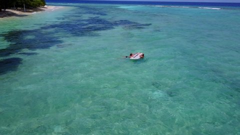 Couple swimming on shallow clear seawater, large green algae thriving around shore of exotic island in Jamaica