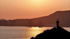 Time lapse video of orange sun falling from sky to behind island mountains on sea, beautiful sunset landscape in Putuo mountain in Zhejiang, China, 4k footage, b roll shot.