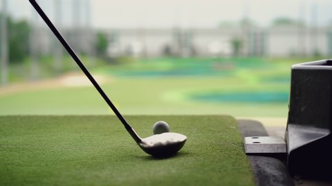 Close-up of golf ball on tee with golf club overlooking driving range at Topgolf