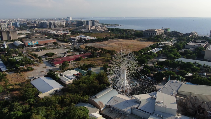 Stable aerial drone view of cityscape,skyline seafront,big ferris wheel from Manila,Philippines