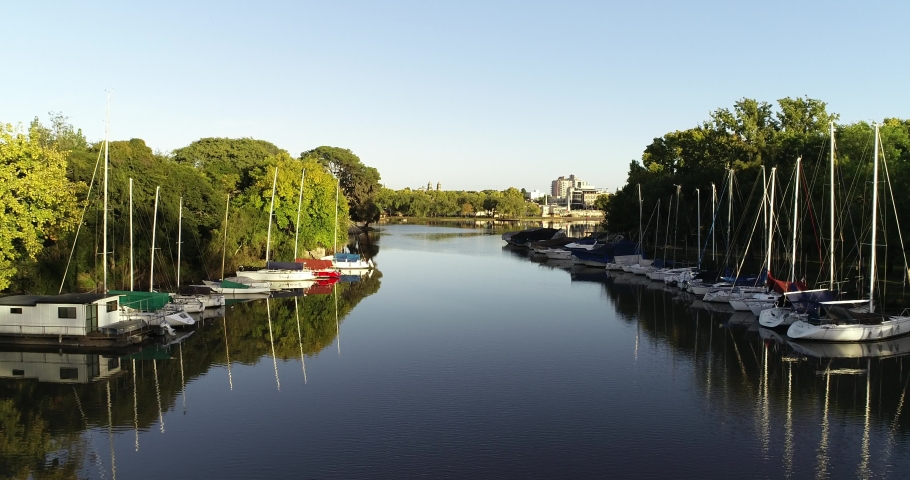 Aerial drone scene flying above river delta with moorings towards city. Natural environment versus civilization. Sunset. Guleguaychu, Entre Rios, Argentina