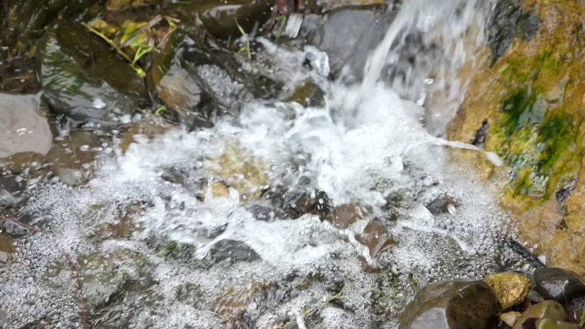 Close-up Little Waterfall, Slowmotion. Water Splash on the Rocks, Unspoiled Nature.
