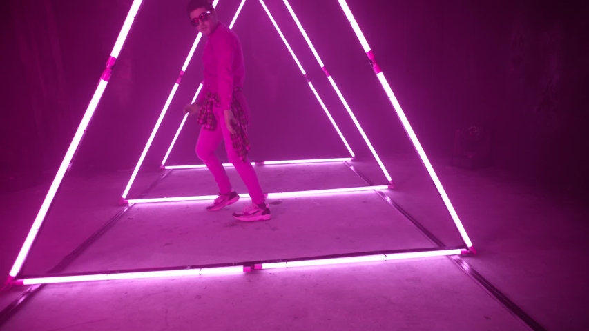 Professional Hip Hop break dancer . Stylish young man dancing with real strobe lights . Against colored background with triangle shape of led lights . Real decoration . Shot on RED EPIC Cinema Camera Royalty-Free Stock Footage #1039853909