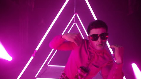 Professional Hip Hop break dancer . Stylish young man dancing with real strobe lights . Against colored background with triangle shape of led lights . Real decoration . Shot on RED EPIC Cinema Camera