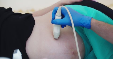 Pregnant woman lying on her side having Ultrasound scan. The doctor carefully examines with the scanner