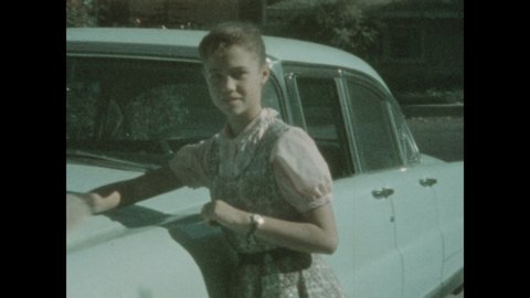 1940s: Teenage girl polishes the hood of a baby blue car Desoto with a polishing mitt.