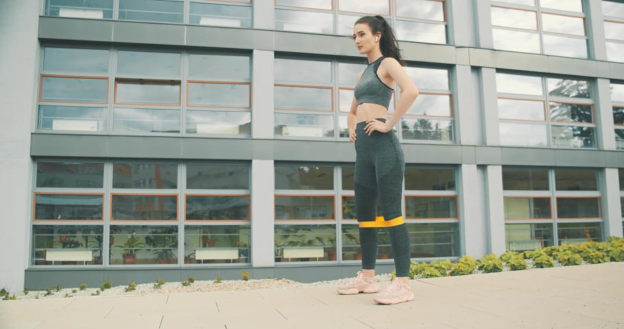 Young woman doing sports in outdoors modern place in city park in summer sunny day under sun light. 4K slow motion video
