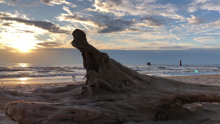 Waves crashing along Lake Michigan shoreline at Grand Haven and Muskegon, MI.  Sand erosion, waves, driftwood, grass, surf, pier, and sunset