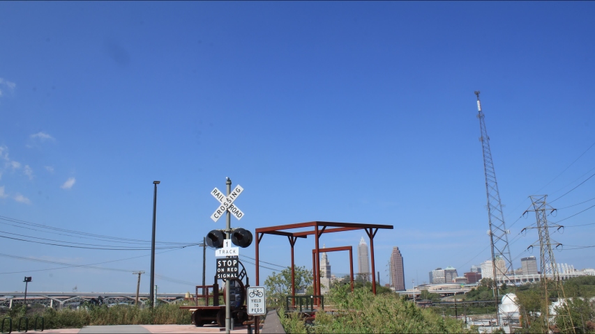 Cleveland, Ohio Towpath trail head for biking and running near downtown industry along the Cuyahoga River. Clear day with some clouds and blue skies and a railroad crossing feature.